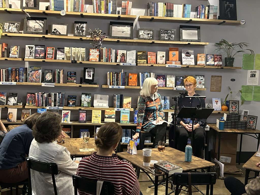 Author Jodi Lorimer answering interview questions before an audience in a bookshop
